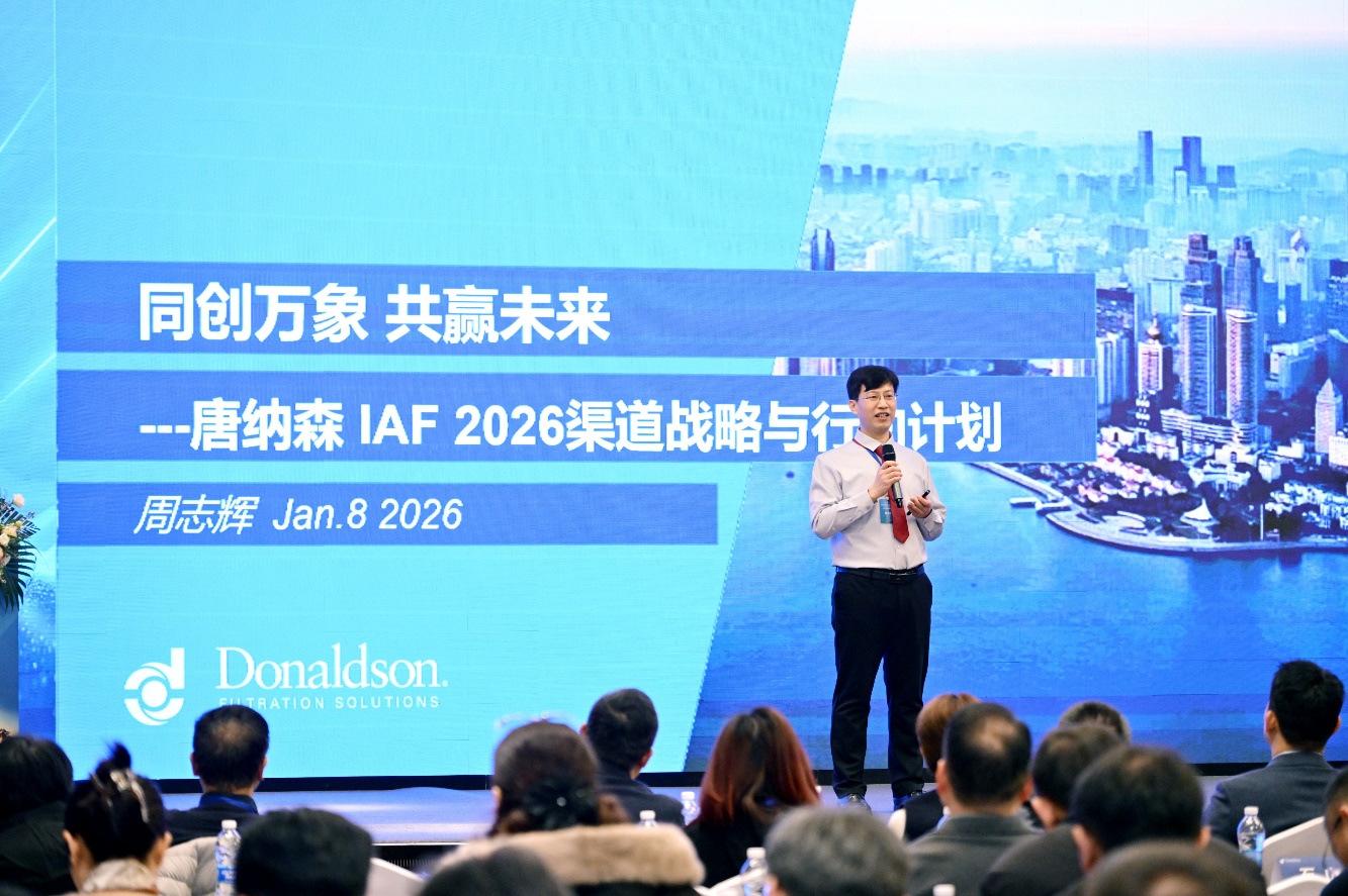 A person standing on a stage with a large screen behind himAI-generated content may be incorrect.